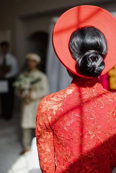 the back of a woman's head with a red hat on her head and people in the background