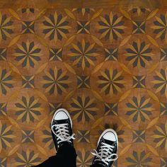 a person standing on top of a wooden floor with black and white shoes in front of them