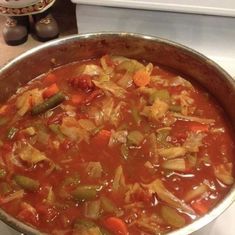 a pot filled with soup sitting on top of a stove next to a white counter