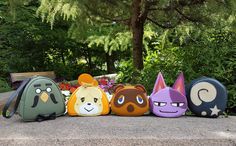 several different colored bags sitting on top of a cement slab in front of some trees