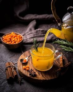 a glass cup filled with orange juice and garnished with rosemary next to a bowl of chickpeas