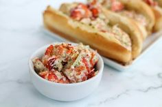 two bowls filled with food sitting on top of a white counter next to some bread