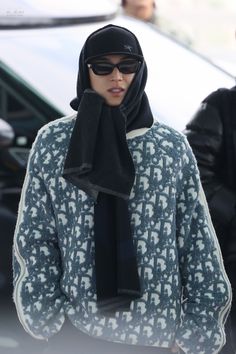 a woman wearing sunglasses and a scarf on her head is standing in front of a car