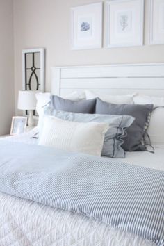 a bed with blue and white pillows in a bedroom next to pictures on the wall