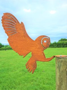 a wooden bird on a post in the grass