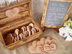 a wooden box filled with heart shaped cookies next to a chalkboard sign and flowers