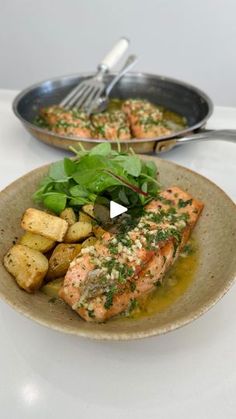 a plate with salmon, potatoes and greens on it next to a frying pan