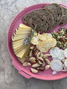 a pink plate topped with different types of cheese and crackers on top of it