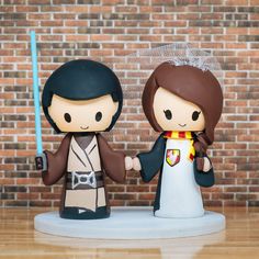 a star wars wedding cake topper with the bride and groom holding hands on a wooden table