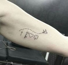 a person's arm with a cross, heart and arrow tattoo design on it