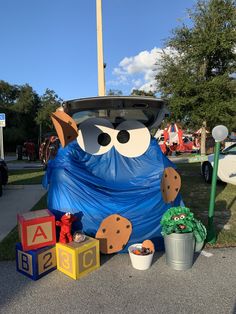 an inflatable blue monster sitting on the side of a road next to toys