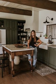 a woman standing in a kitchen next to a table