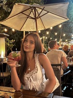 a woman sitting at a table holding a drink