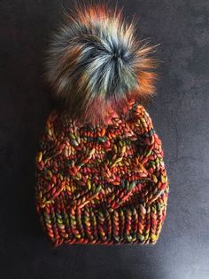 a multicolored beanie with a fuzzy pom - pom on top