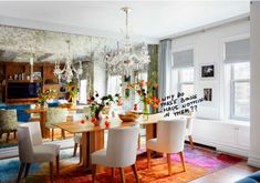 a dining room table with white chairs and a chandelier hanging from the ceiling