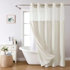 a white bath tub sitting under a window next to a shower curtain in a bathroom