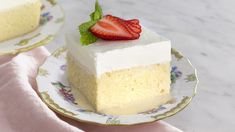 a piece of cake with white frosting and a strawberry on top sitting on a plate