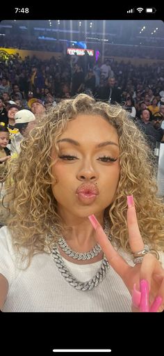 a woman making a peace sign with her fingers in front of an audience at a sporting event