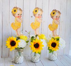 three vases with sunflowers and baby dolls in them