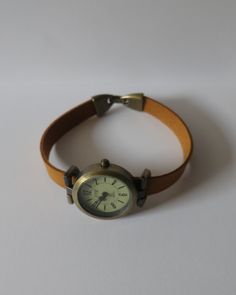 This is a simple and classic design watch for women. The watch head is made in aged bronze finish alloy, free of nickel and lead, round shape, 1 inch diameter. The quadrant is cream color with 3 needles. The watch is battery operated and has a new battery inside. The band is made with synthetic suede, camel color. The band will be made to fit to your wrist, please, choose your wrist measurement when you buy it. The closure is a folding over type clasp, also made in alloy aged bronze finish. Come Adjustable Watch With Metal Dial For Everyday Use, Vintage Brown Leather Watch Accessories For Everyday Use, Everyday Handmade Brown Watch, Brown Watch Accessories With Metal Dial And Adjustable Fit, Brown Adjustable Watch Accessories With Metal Dial, Adjustable Brown Wrist Strap Watch Accessories, Handmade Adjustable Brown Watch Accessories, Classy Womens Watches, Brown Watch Accessories With Polished Finish, Round Dial