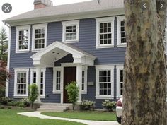 a blue house with white trim on the front door and windows is seen in this image