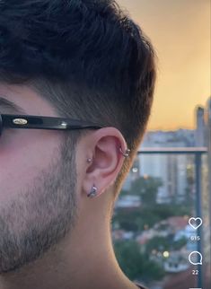 a man with piercings on his ears looking out at the city