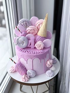 a birthday cake decorated with pink icing and candy decorations on a table next to a window