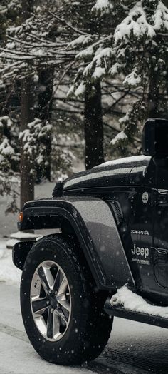 a jeep parked on the side of a road covered in snow with trees behind it