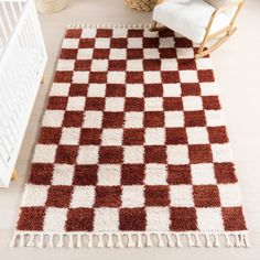 a brown and white checkered rug on the floor next to a baby crib