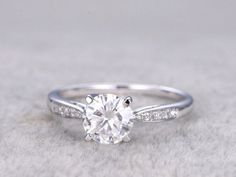 a white gold ring with a round brilliant cut diamond in the center and pave set side stones around the band