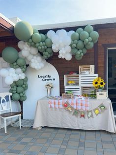 a table topped with balloons and flowers next to a white sign that says locality grown