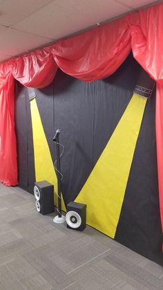 an empty room with red curtains and speakers on the floor, in front of a black backdrop