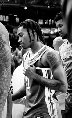 a man with dreadlocks standing next to other men in basketball uniforms and tattoos