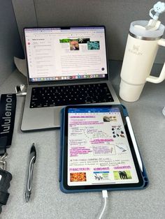 an open laptop computer sitting on top of a desk next to a cup and pen