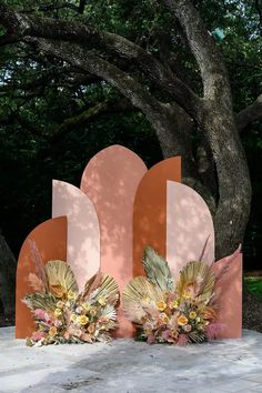 two large sculptures with flowers on them in front of a tree