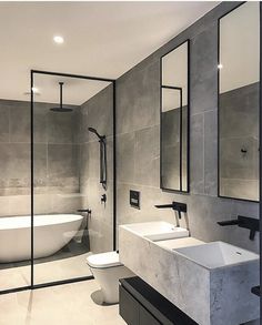 a bathroom with two sinks and a bathtub in the middle, surrounded by mirrors