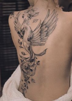 a woman's back with a bird tattoo on it