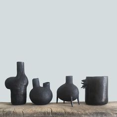 five black vases sitting on top of a wooden table