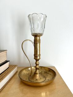 a glass candle holder sitting on top of a wooden table next to a stack of books