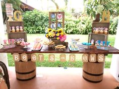 a table topped with lots of desserts on top of wooden barrel tables covered in letters