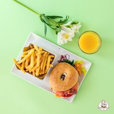 a hamburger and french fries on a plate with a glass of orange juice next to it