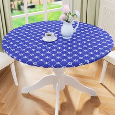 a blue table cloth with white flowers and a teapot on it in front of a window