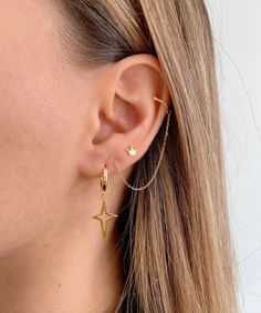 a close up of a woman's ear wearing gold earrings with stars on them