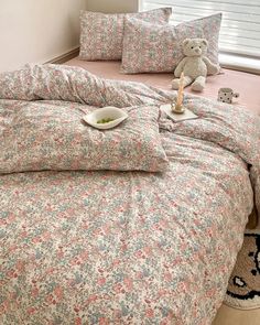 a teddy bear sitting on top of a bed next to pillows and pillowcases