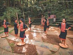 a group of young women standing on top of a stone floor in front of trees