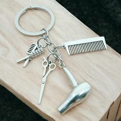 a pair of scissors, comb and hair clip on a wooden table with a metal keychain