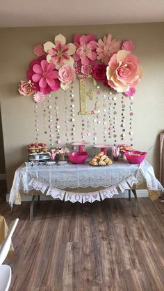 a table topped with lots of pink flowers and cupcakes on top of it