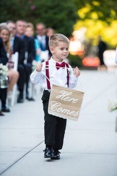 a little boy in a suit and tie holding a sign