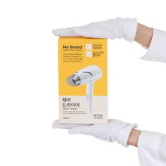 a pair of white gloves holding an electronic device in front of a box with no brand written on it