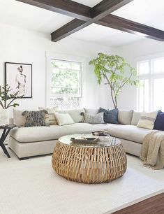 a living room filled with lots of white furniture and pillows on top of a rug